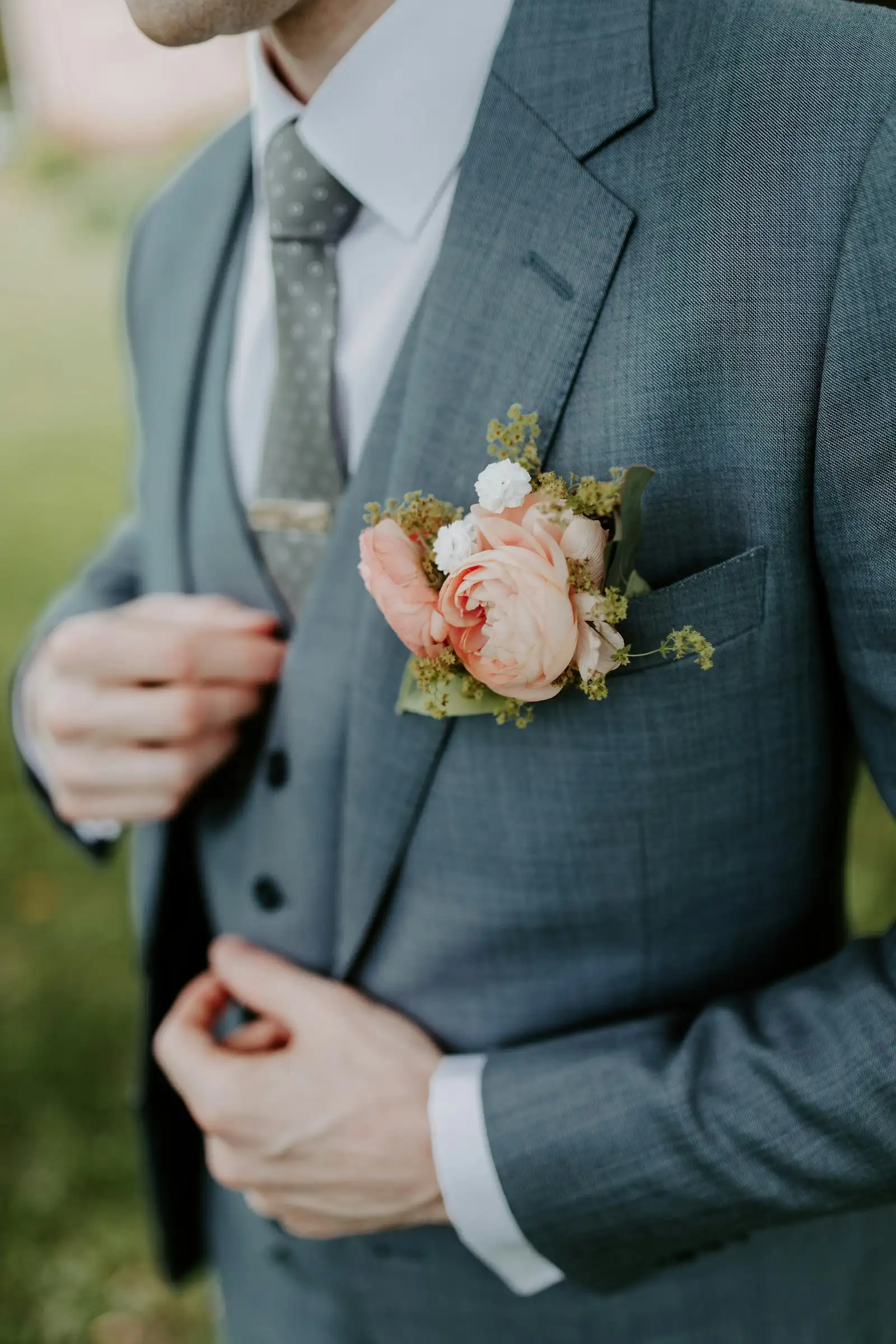 A groom with a blush boutonniere pinned to his lapel