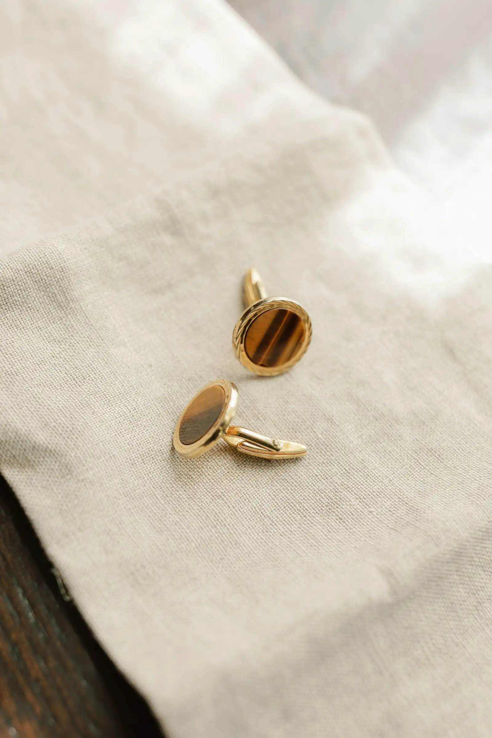 A pair of gold cufflinks on dark cloth