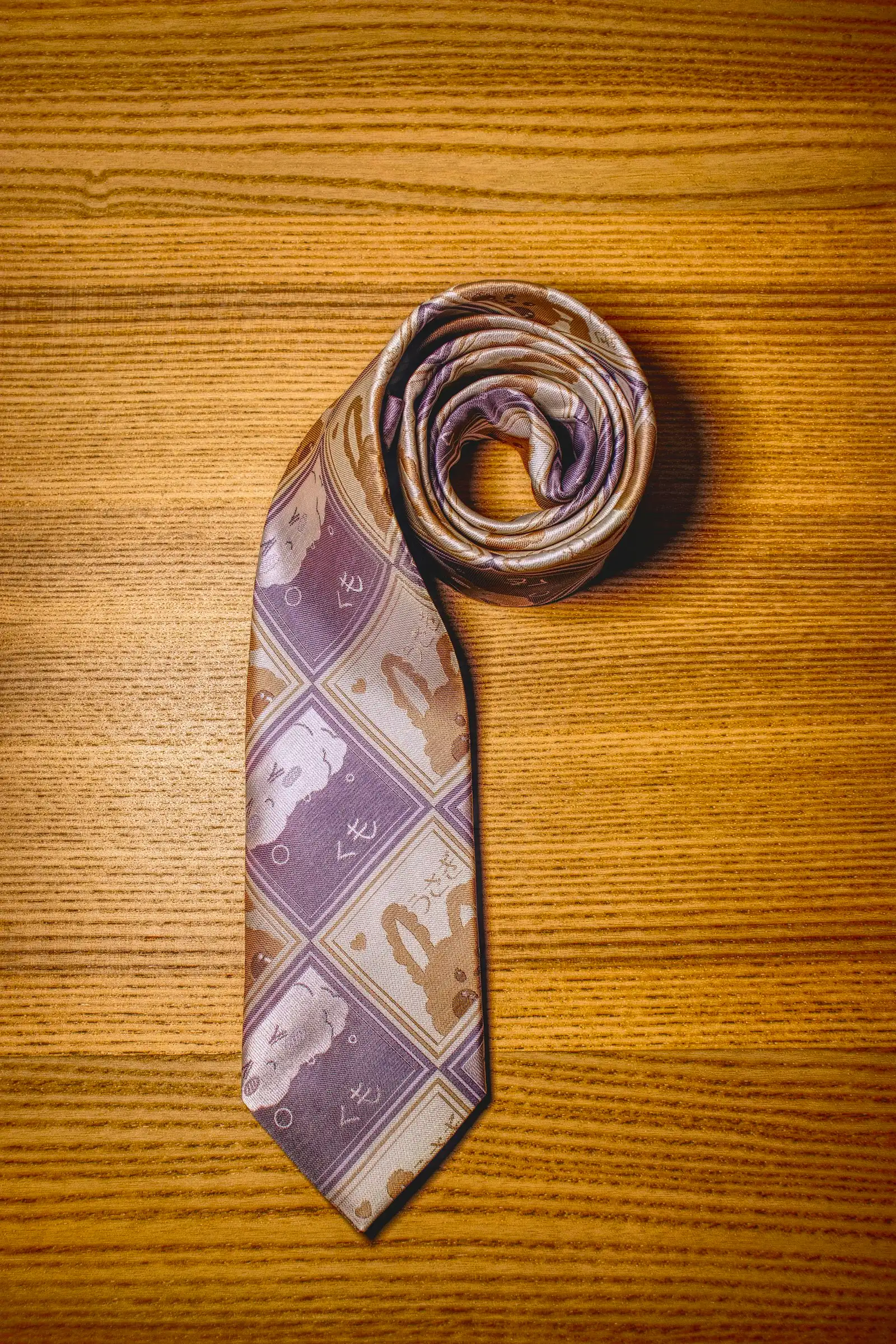 A rolled silk tie on a dark surface